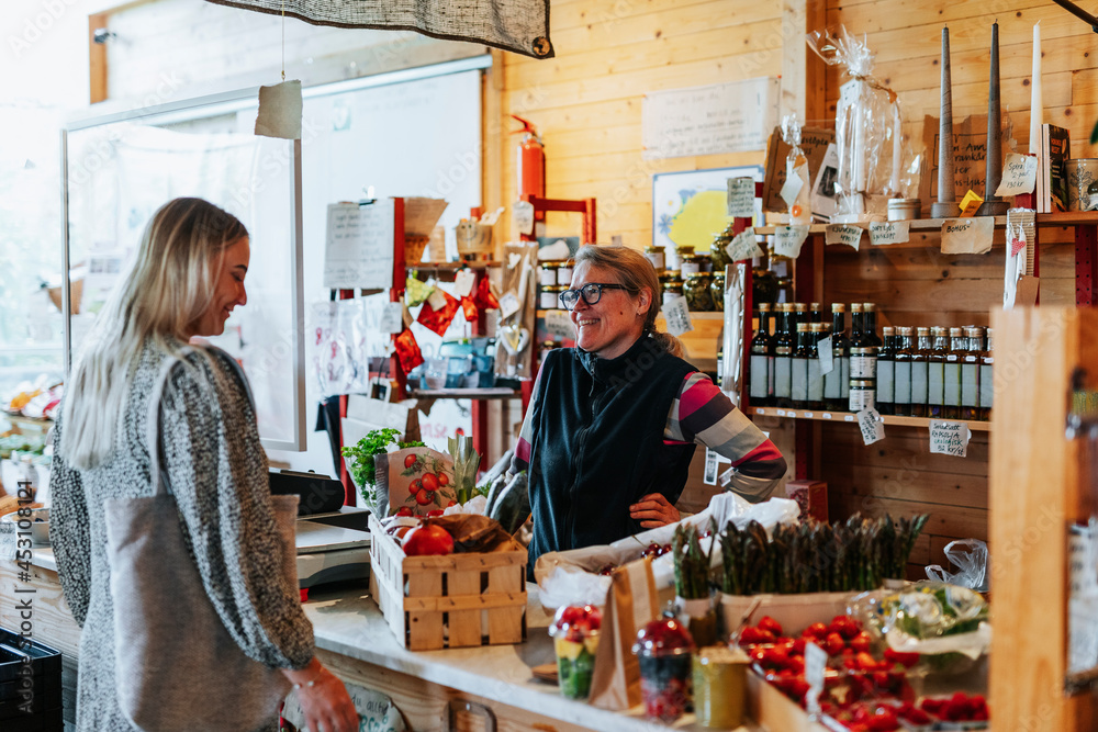 Customer talks to shopowner at checkout counter