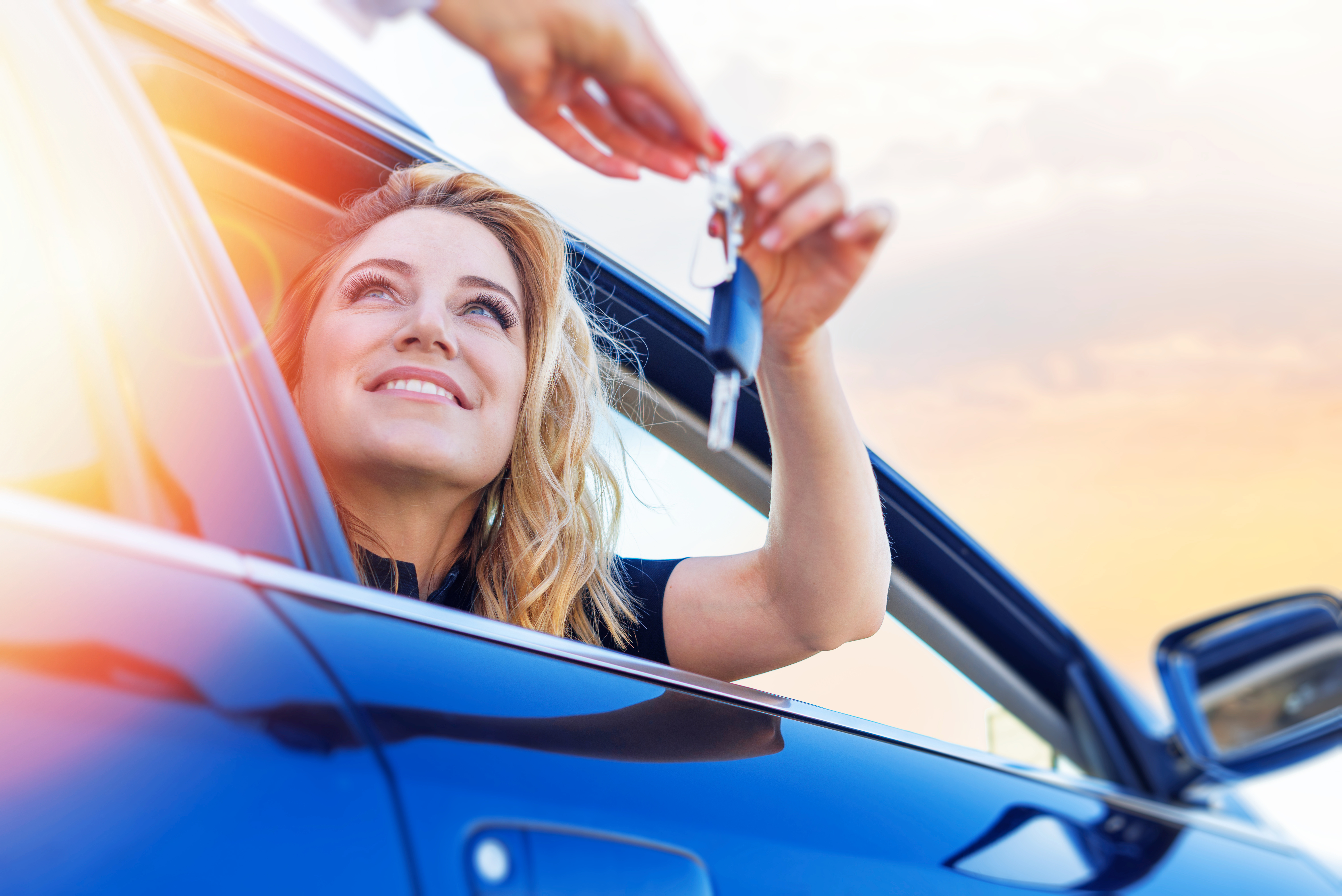 A woman holding the key to buy the car