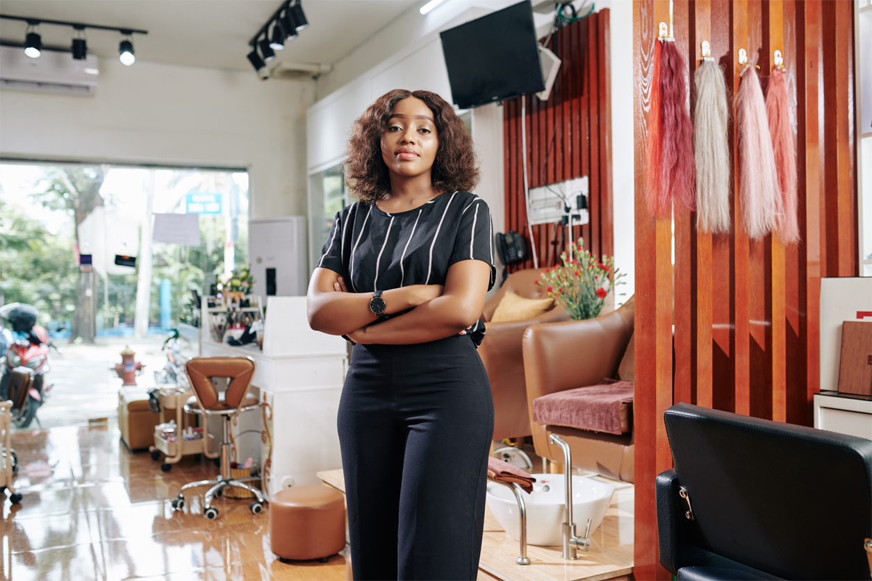 Young woman standing in her beauty salon that she obtained by using a credit union business loan.