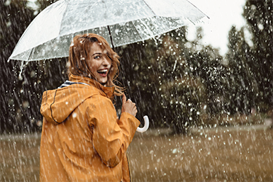 A woman uses an umbrella to shelter from the rain and uses overdraft protection to avoid fees.